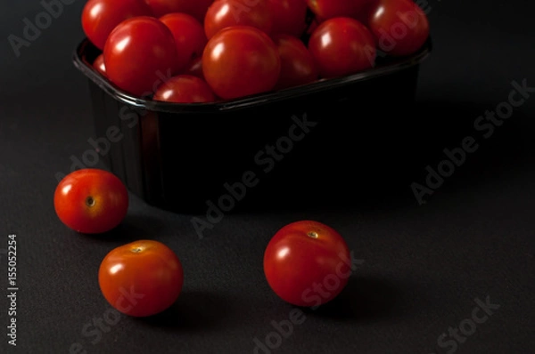 Obraz Tomatoes on black background.