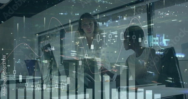 Obraz Professionals in blazers reviewing financial charts on computer in office at night, with coffee mug