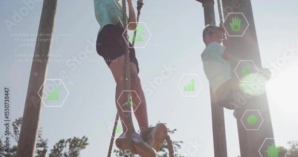 Fototapeta Climbing school-aged boys ascending wooden poles using thick ropes at park, with green data icons