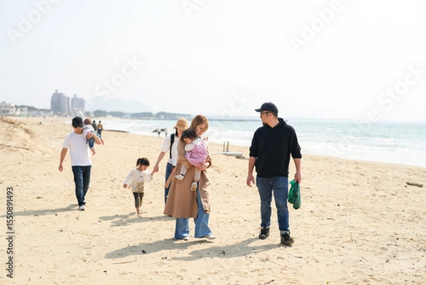 Fototapeta In early March, Japanese families enjoy the beach together: a 6-month-old baby, a 1-year-old girl, a 3-year-old girl, and parents in their 30s. A cheerful springtime scene filled with warmth and joy.