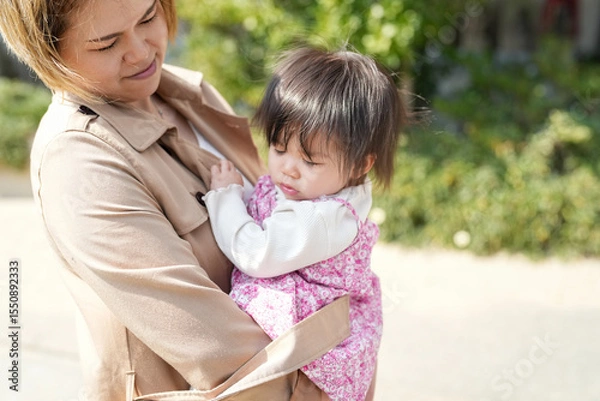 Fototapeta In early March, a Japanese mother in her 30s holds her 1-year-old daughter on a sandy beach by the sea. A heartwarming springtime moment filled with warmth and tenderness along the quiet shoreline.
