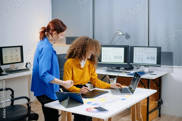 Fototapeta Creative UX UI design team collaborating on mobile interface in a bright tech office. Teamwork, planning, and modern workflow