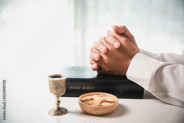 Obraz During the holy communion ceremony in church, a hand is extended in faith to receive the sacred sacrament, reflecting the spiritual and religious worship central to Christianity.
