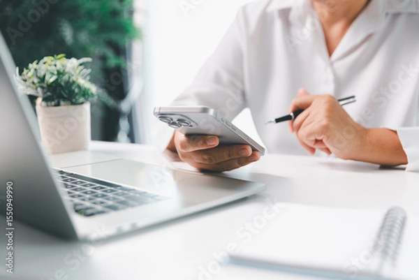 Obraz Close-up scene, a female seated at a table holds a smartphone, spending time on modern e-date services and social media through a mobile app, illustrating the wireless concept of digital usage.