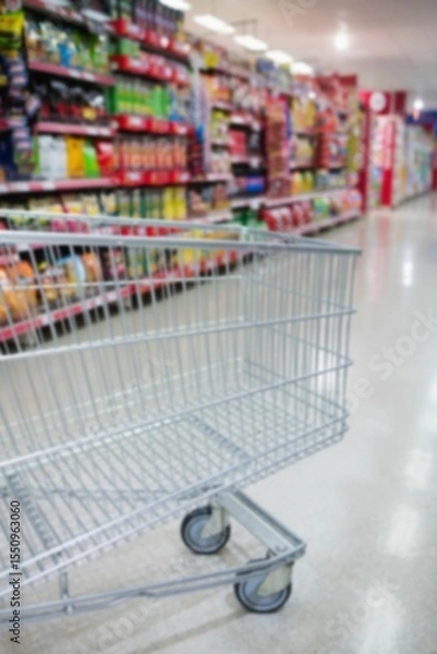Obraz Cropped image of shopping cart in supermarket aisle