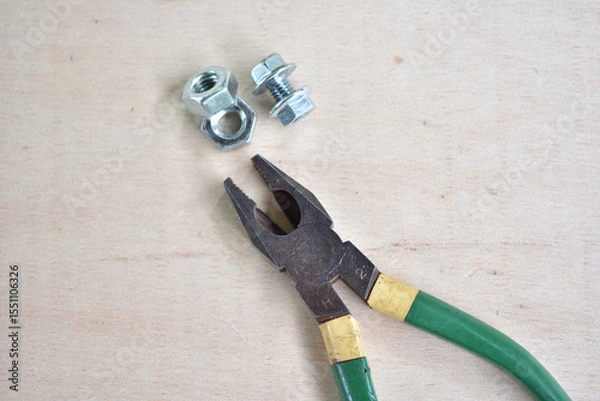 Fototapeta 木の板の上に置かれたペンチとネジ