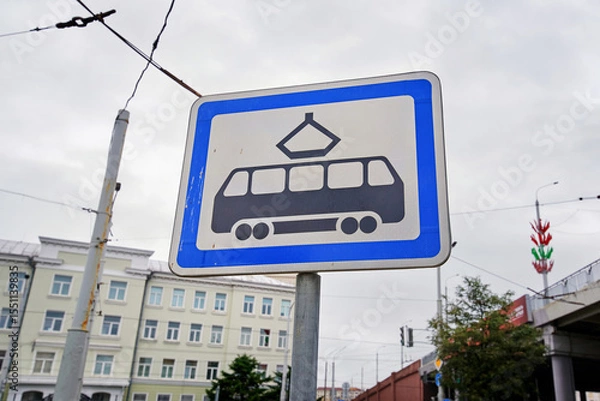 Fototapeta Road sign marking tram stop location stands tall against cloudy sky, urban public transit infrastructure and electric streetcar accessibility. Tram stop sign captured with cloudy sky background