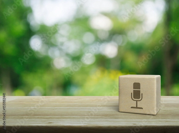 Fototapeta Microphone flat icon on wood block cube on wooden table over blur green tree in park, Business communication concept
