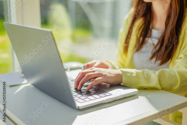 Fototapeta Cropped hands of businesswoman typing on laptop at office desk. Modern workplace, technology and professional lifestyle concept. Independent woman typing on laptop in coworking space.
