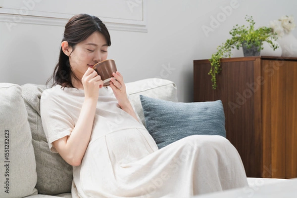 Fototapeta ソファーで飲み物を飲む妊婦　ライフスタイルイメージ