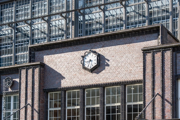 Fototapeta A large wall clock mounted on the exterior of Berlin Friedrichstrase station. Historic architecture with detailed brick and ironwork.