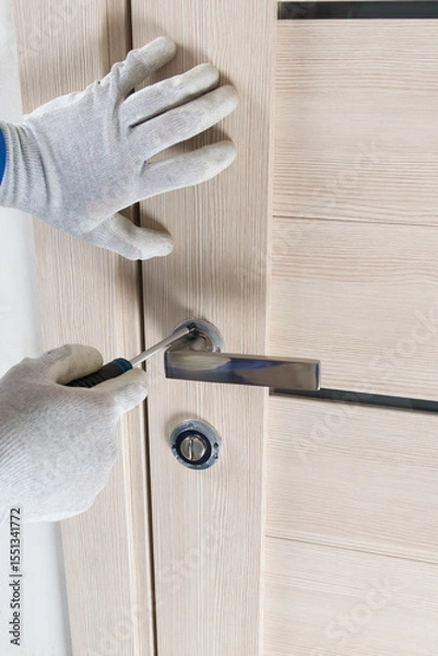 Fototapeta the master tightens the screw for installing the interior lock with a screwdriver