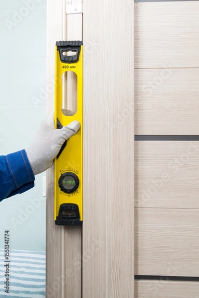 Fototapeta a master in a blue uniform checks the correct installation of a door in an apartment
