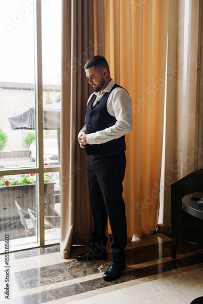 Obraz A young man in a vest and a white shirt by the window.
