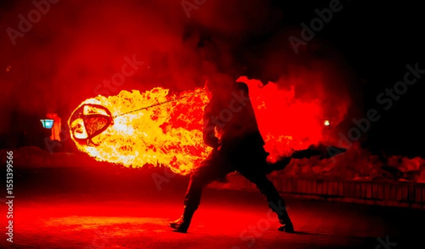 Fototapeta Fire performer demonstrates skillful control of flaming poi during nighttime outdoor event