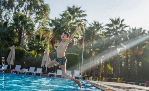 Fototapeta Caucasian boy kid jumping into swimming pool at summer resort, summer activity travel concept