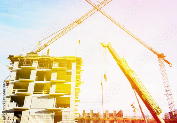 Obraz Tower crane on bright sunset. House and buildings construction on sunrise. Housing renovation, real estate. Crane on formwork in Built environment. Cranes on pouring concrete on Construction site.