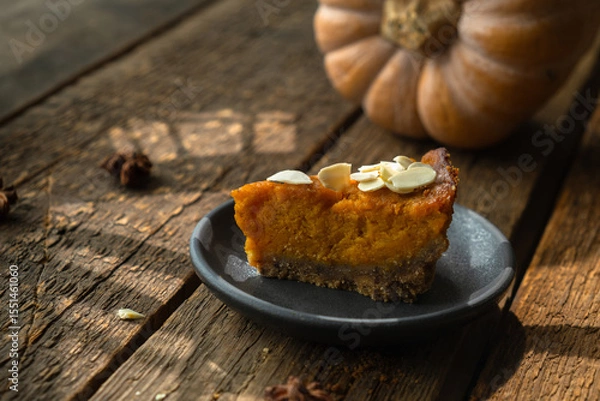 Fototapeta Delicious slice of pumpkin pie for Thanksgiving, adorned with sprinkle of almonds. 