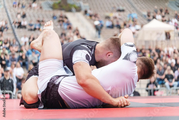 Fototapeta Two athletes competing in no-gi Brazilian jiu-jitsu BJJ match on outdoor mat