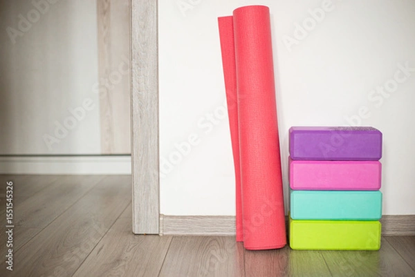 Fototapeta Colorful yoga mats and blocks arranged neatly in a home studio next to a light wooden floor