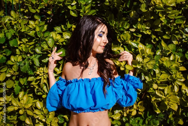 Obraz Beautiful woman posing on the backround with green plants.