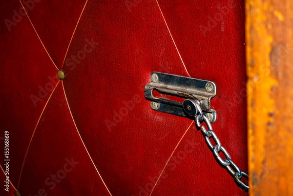 Obraz Old Door Chain Lock on Red Leather Upholstered Door — Vintage Security Lock, Interior Safety Element, Retro Hardware, Home Entrance Protection
