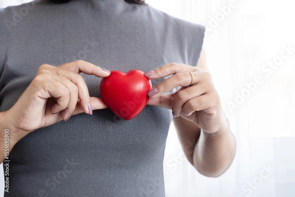 Obraz Closeup of woman hand holding a red heart shaped object, representing heart health awareness, early medical checkups, cardiology care and reminders for World Heart Day