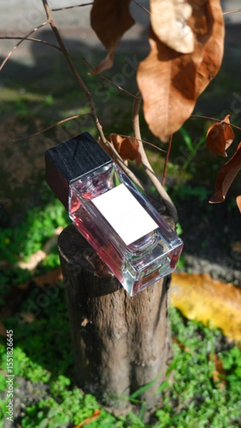Obraz perfume bottle mockup with plain white label on the natural woods background