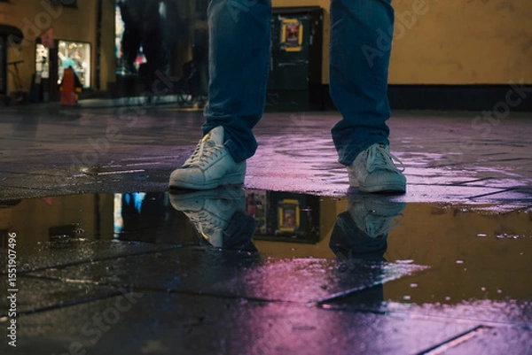Obraz A man standing next to a puddle