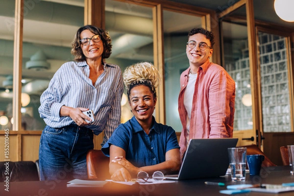Fototapeta Smiling group of three friends together in a comfortable office space