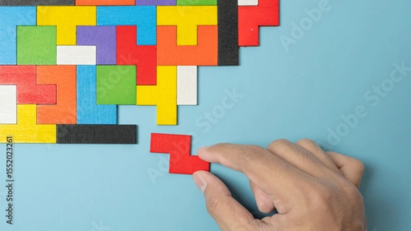 Obraz hand connecting geometric shape block with colorful wood puzzle pieces. logical thinking, business logic, Conundrum, decision, solutions, rational, mission, success, goals and strategy concepts