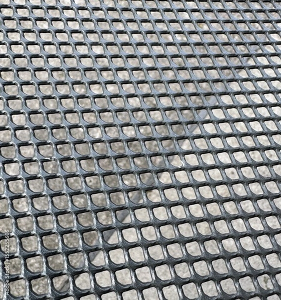 Fototapeta View of pavement through geometric metal grid