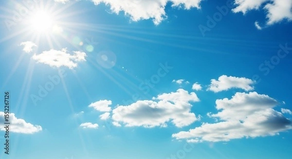 Fototapeta Bright Sun with Sunrays and Fluffy Clouds in a Blue Sky

