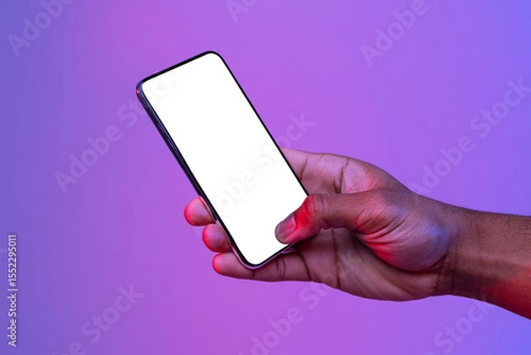 Obraz Black Male Hand Holding Smartphone With Glowing White Screen Under Neon Light Over Purple Background, Unrecognizable African American Man Showing Free Copy Space For Your App Design, Mockup Image
