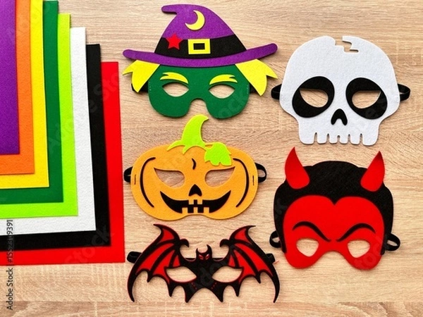 Fototapeta Halloween. DIY Felt Halloween Masks. Felt masks and felt sheets are lying on the table. Set of Various Masks, monsters, Pumpkin, Devil, Witch, Skeleton, Bat, DIY Toys, Dress Up Mask, Game Accessories.
