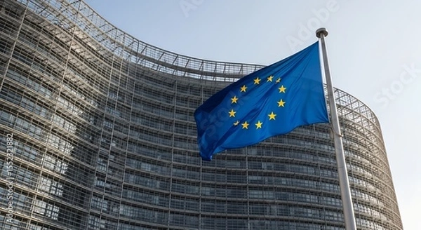 Fototapeta Modern glass building with EU flag waving in front. Headquarters of European Commission symbolizing governance, unity, and politics in the European Union.