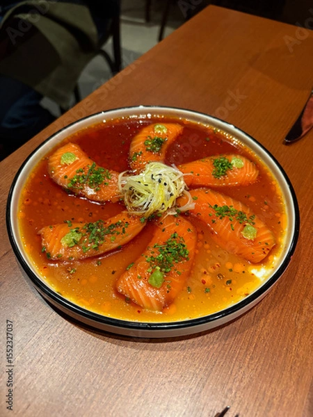 Fototapeta A plate of salmon sashimi in a broth sauce.