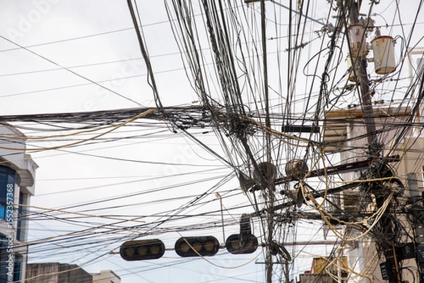 Obraz Chaotic overhead power lines and tangled cables for concepts of infrastructure problems, urban overload, or communication failure