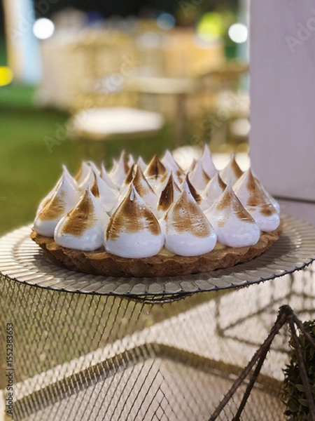 Fototapeta Traditional celebration cake. Closeup view of a Lemon pie with delicious meringue, in a social event with a beautiful gala setting