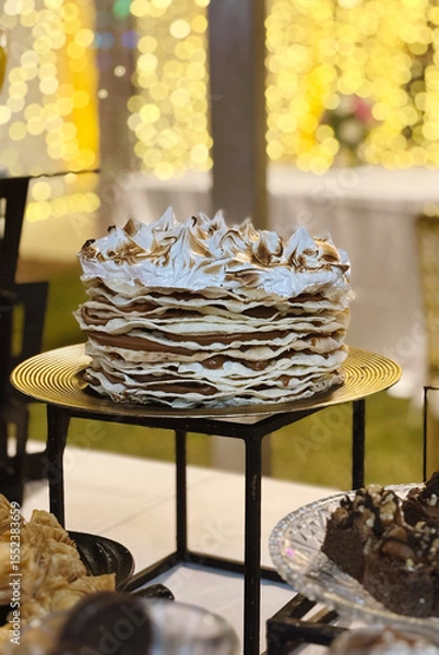 Fototapeta Traditional argentinian dessert. Closeup view of a Rogel cake with crispy layers, dulce de leche and meringue, in a social event with a beautiful gala setting