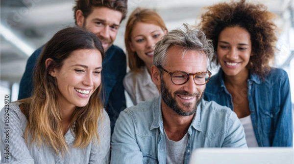 Obraz Smiling diverse group of people working together on laptop in modern office, showing teamwork and positive collaboration atmosphere