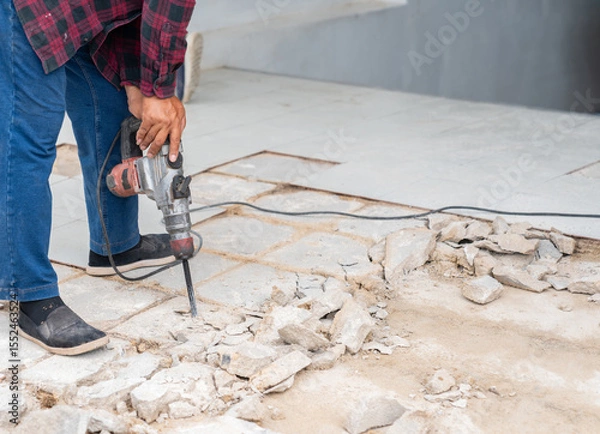 Fototapeta The worker is using a jackhammer to remove the old tiled concrete floor.