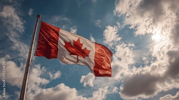 Fototapeta Canadian Flag flailing in the wind. Blue sky with clouds in background