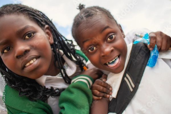 Fototapeta Premium close-up of happy African schoolchildren in uniforms, laughing together outdoors. A powerful and uplifting image capturing real joy, childhood, and cultural connection.