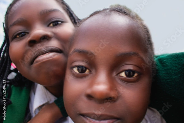 Fototapeta Premium close-up of happy African schoolchildren in uniforms, laughing together outdoors. A powerful and uplifting image capturing real joy, childhood, and cultural connection.