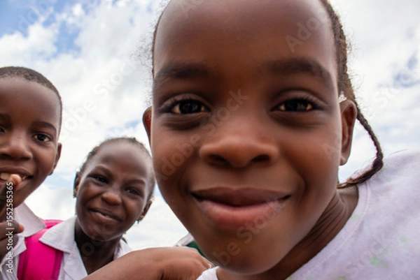 Fototapeta Premium close-up of happy African schoolchildren in uniforms, laughing together outdoors. A powerful and uplifting image capturing real joy, childhood, and cultural connection.