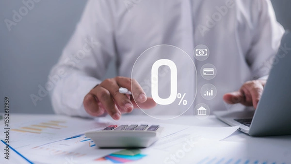 Obraz A person using a calculator and laptop with a prominent 0% icon overlay, representing zero interest rates, financial incentives, loan offers, and strategic cost management in banking and finance.