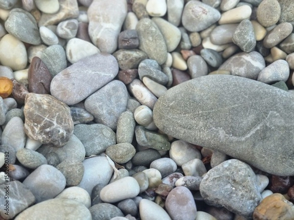 Fototapeta Natural smooth pebbles in various colors and sizes captured closely on the beach