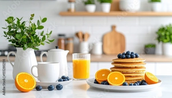 Fototapeta A delicious breakfast scene featuring fluffy pancakes, fresh blueberries, oranges, and a refreshing glass of juice.