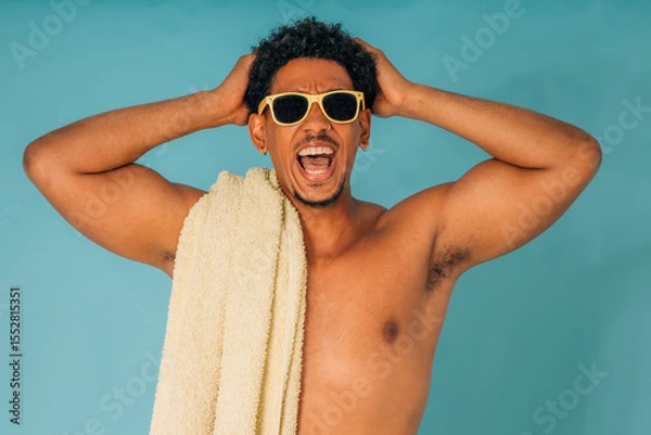 Obraz young latino man shouting with sunglasses and towel in swimsuit isolated on background, summer